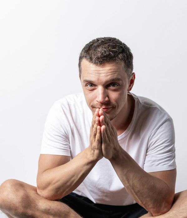 Person meditating peacefully with a calm expression in a minimalist setting.